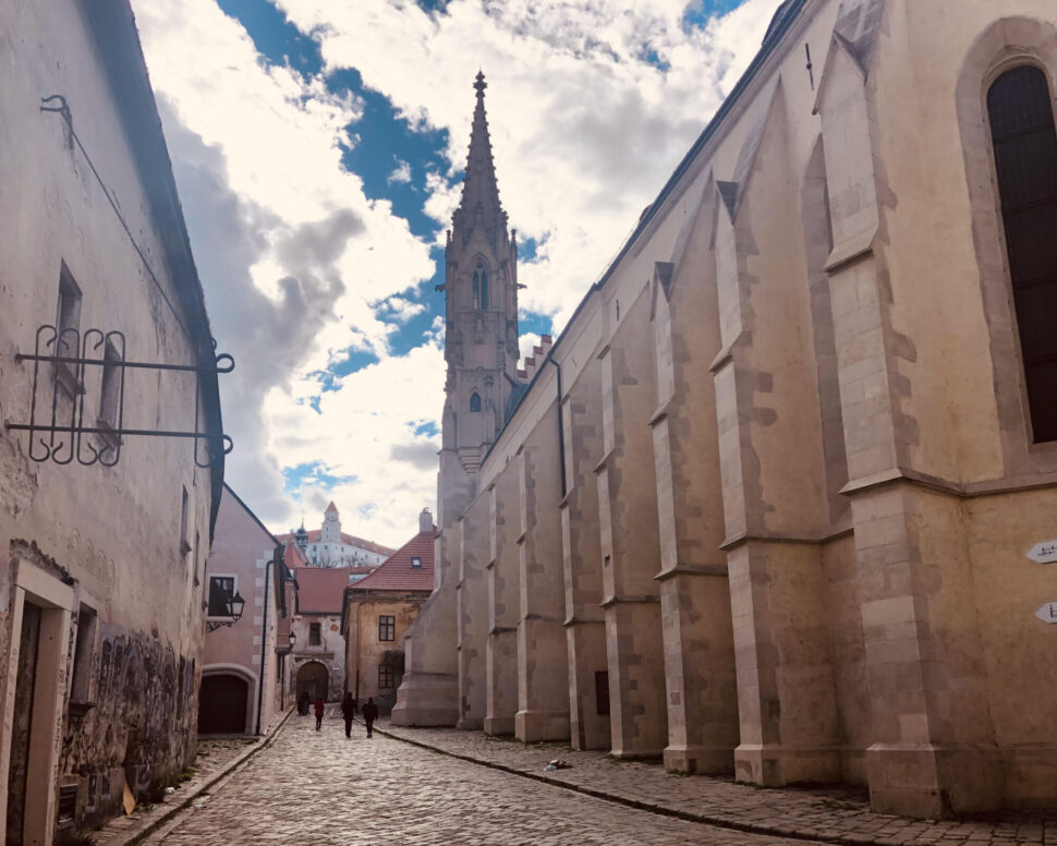 Farská ulica uprostred s výhľadom na Bratislavský hrad, vpravo bývalý kostol Povýšenia sv. Kríža známeho ako Klarisky, vľavo renesančný farský dom.